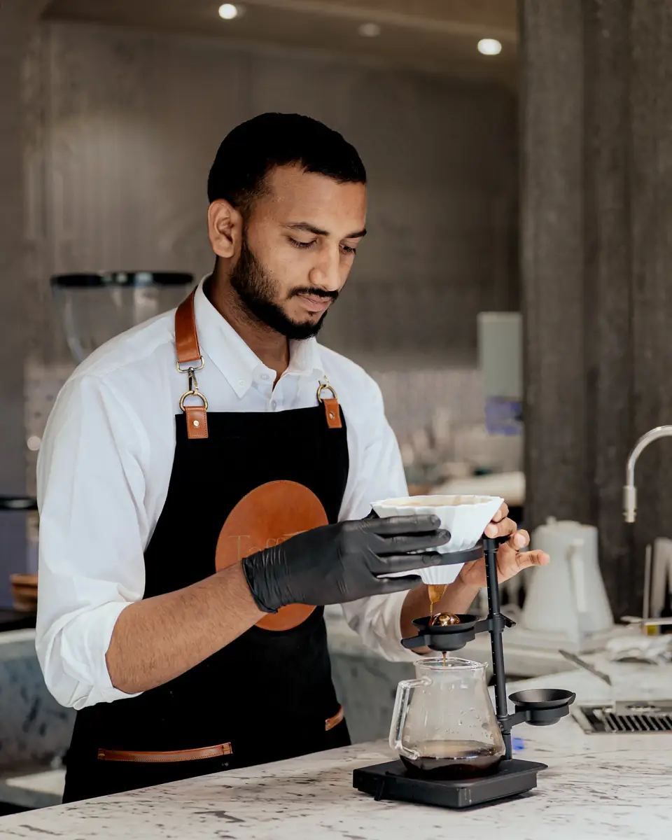 A barista in a Taffeta apron setting up a pour-over on the scale