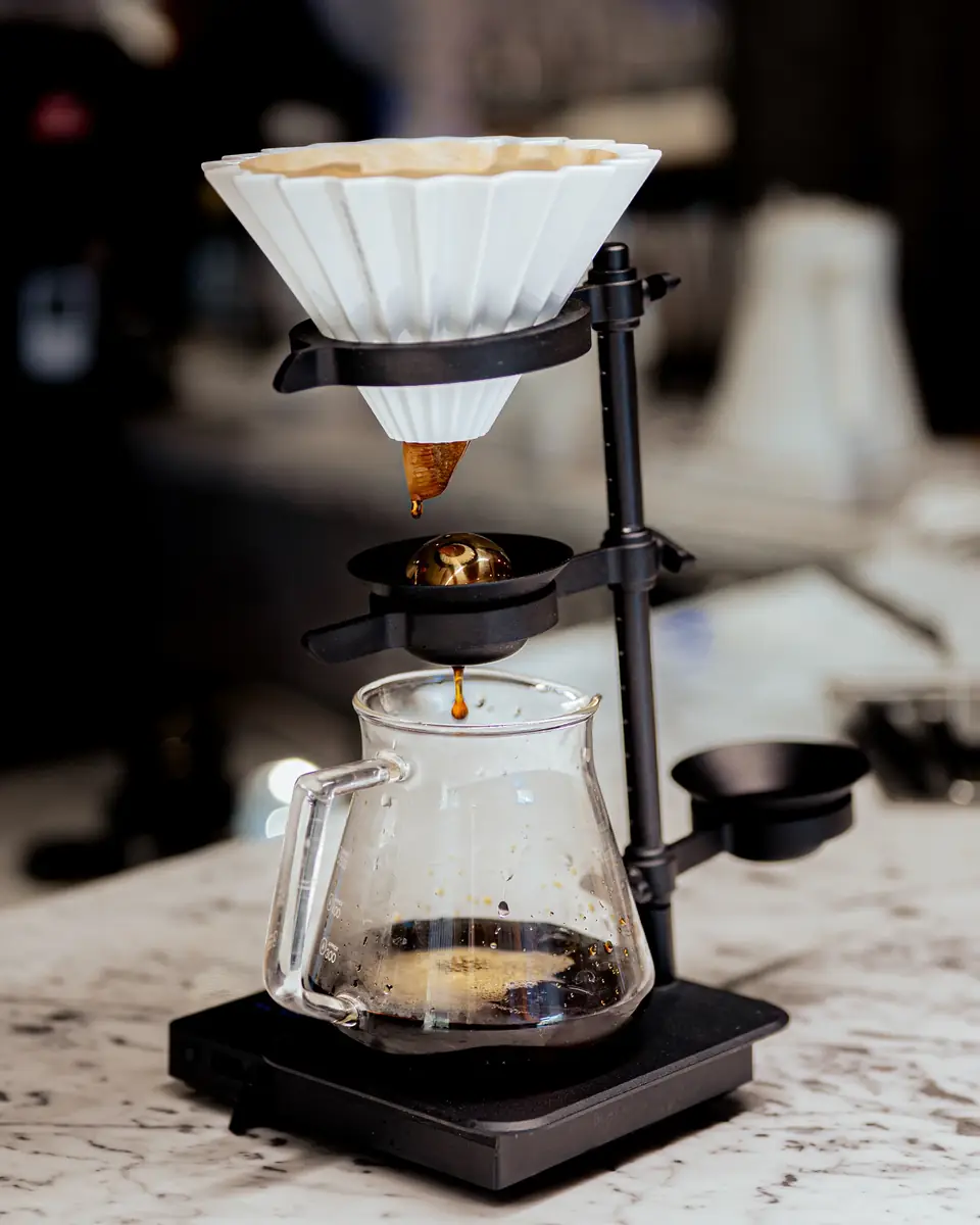 Coffee dripping from a ceramic pour-over cone into a glass server