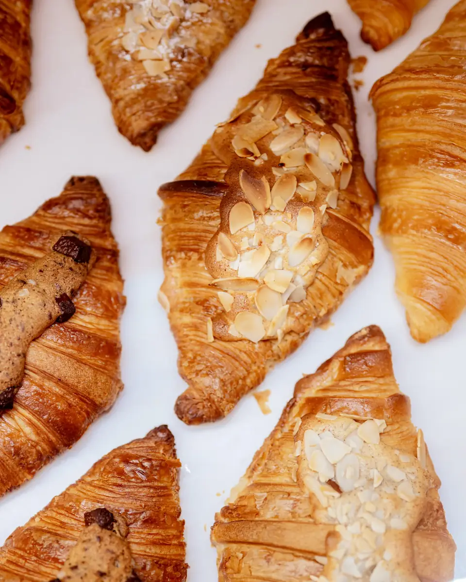 Almond croissants and chocolate croissants laid out on white paper