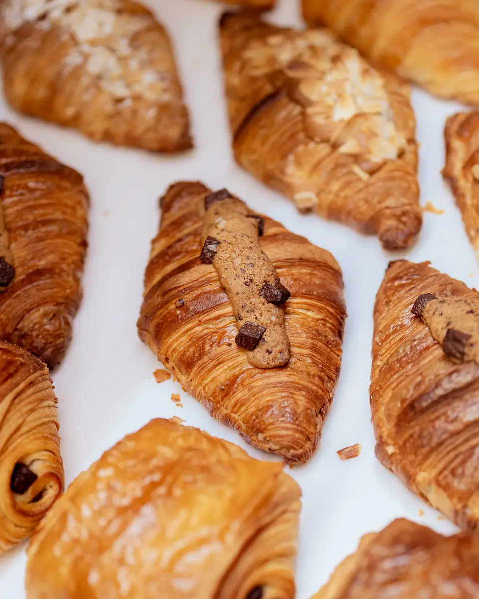 Croissants with chocolate and almond toppings arranged in rows