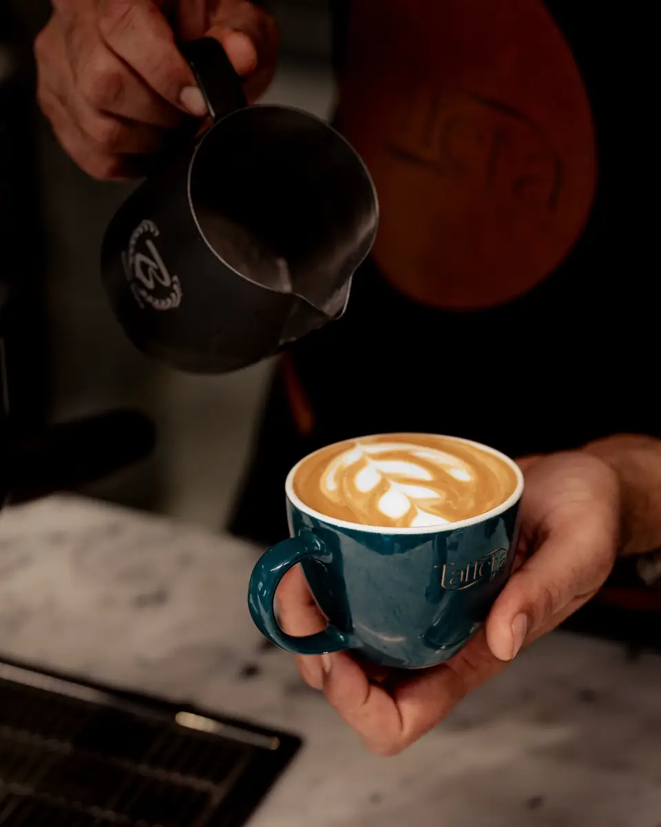 A finished tulip latte art in a teal Taffeta cup