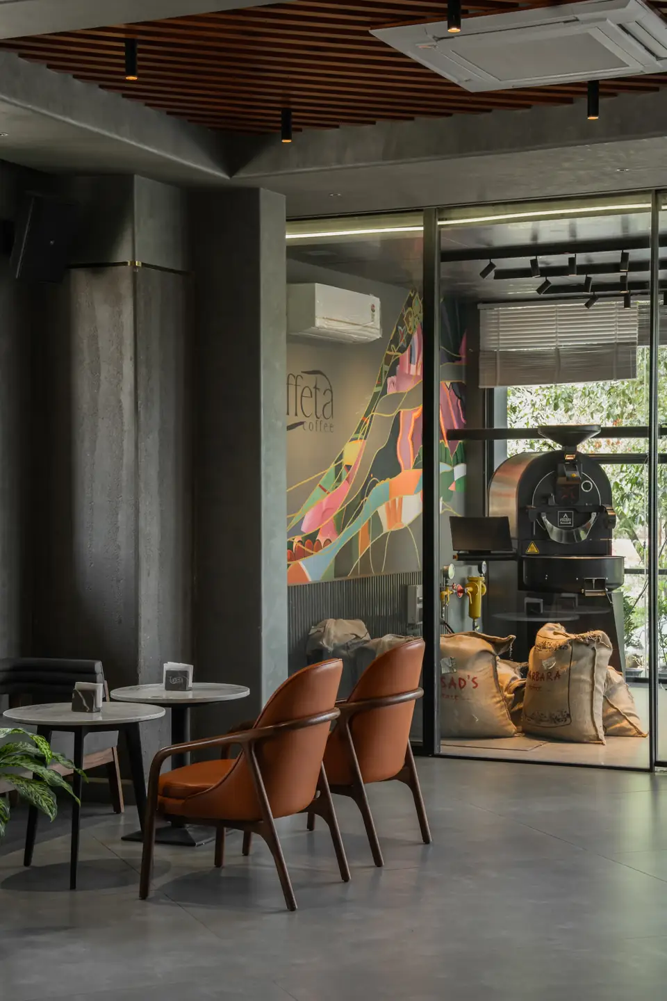 Taffeta's café floor with leather armchairs, a glass-walled roastery and burlap coffee sacks behind