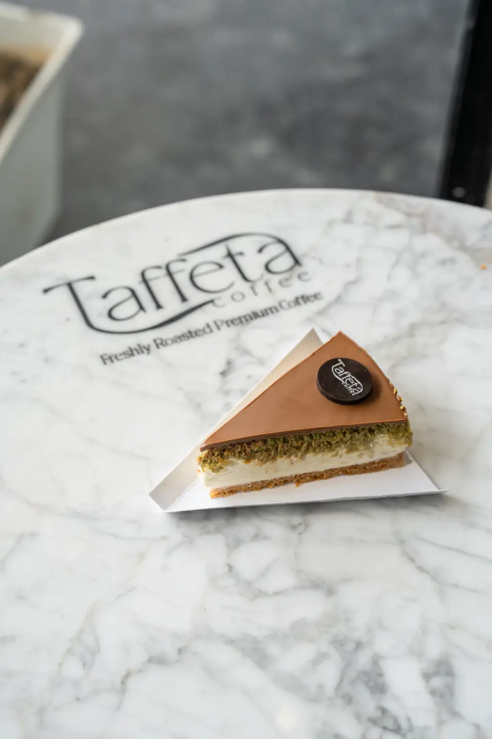 A slice of layered cake on a marble table printed with the Taffeta logo