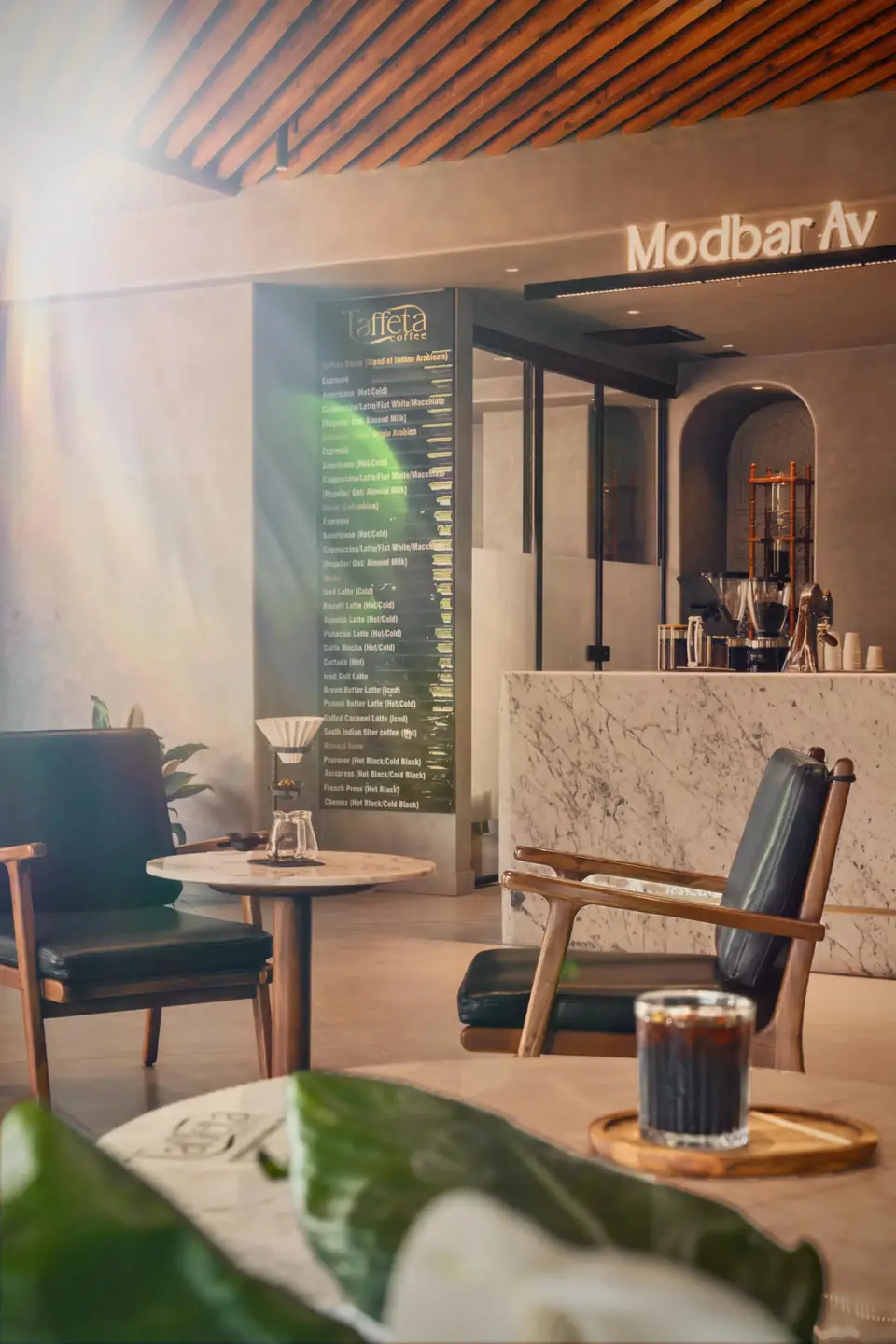 The Modbar Avenue counter seen from the lounge, with a cold brew on a side table